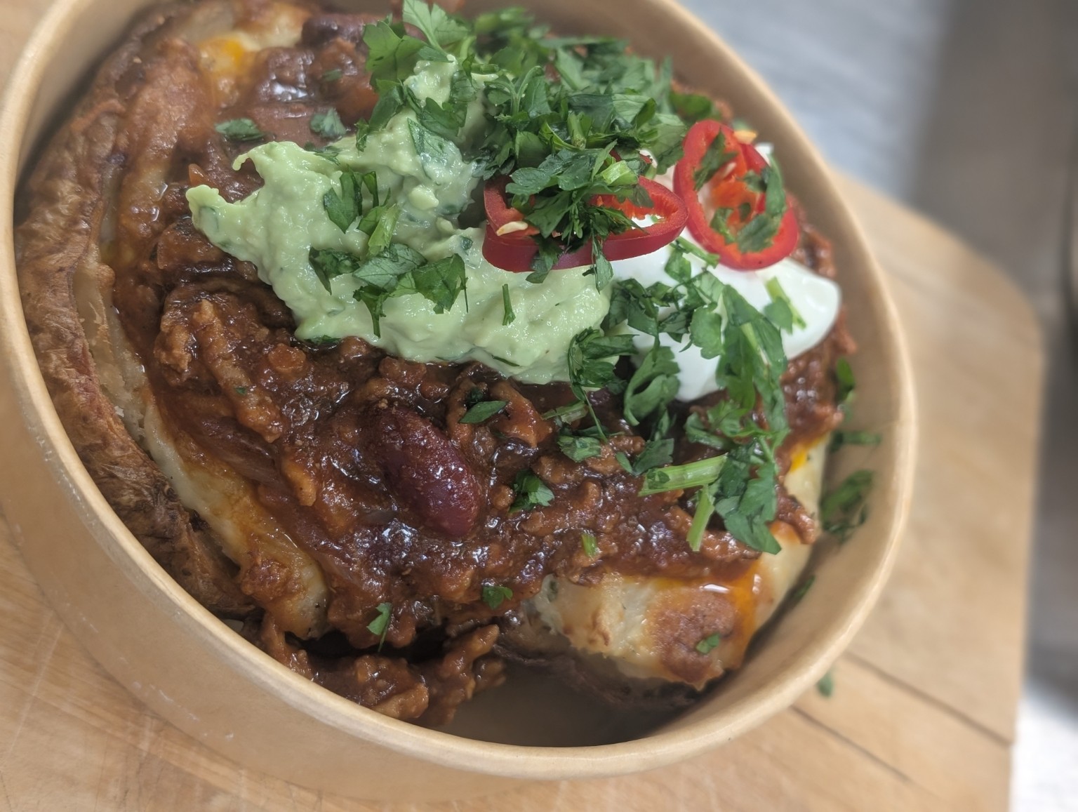 Jacket potato topped with chilli, guacamole, cream and fresh herbs