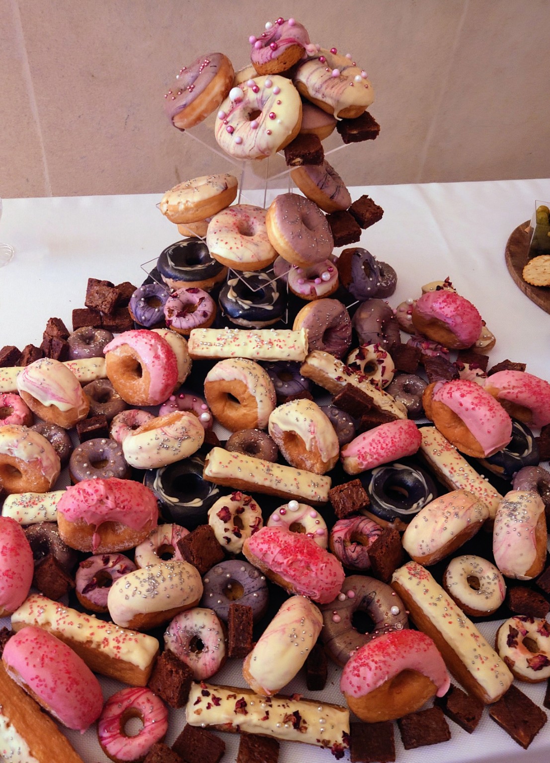 A celebration dessert table of iced doughnuts, brownies and decorated sweet treats