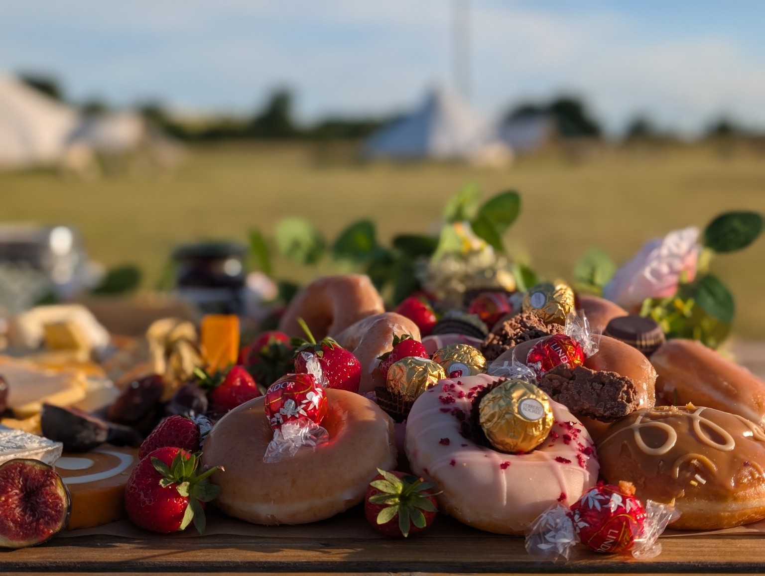 Doughnuts, chocolates and strawberries on an outdoor dessert board
