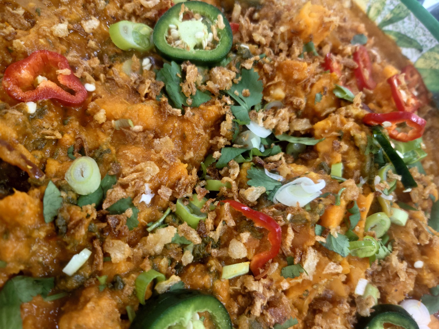 A colourful sharing dish topped with sliced chillies, herbs and crisp onions