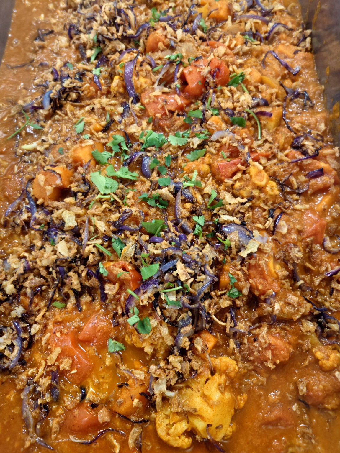 A colourful vegetable dish topped with herbs and crisp onions